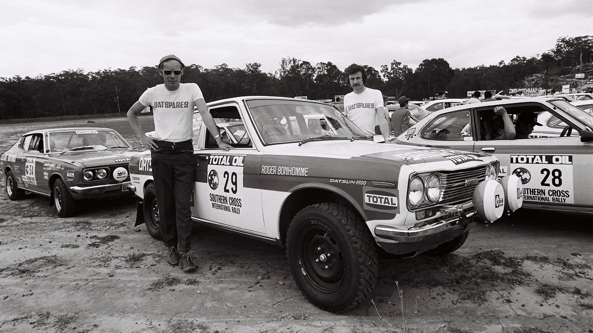 Two men standing next to a rally car.
